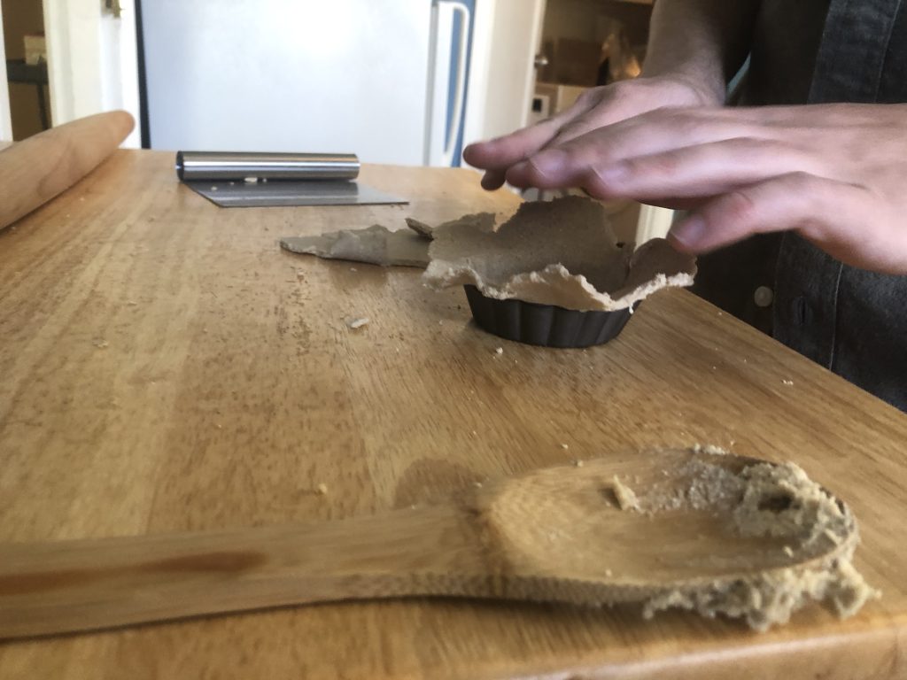 Someone presses dough into a small tart pan.