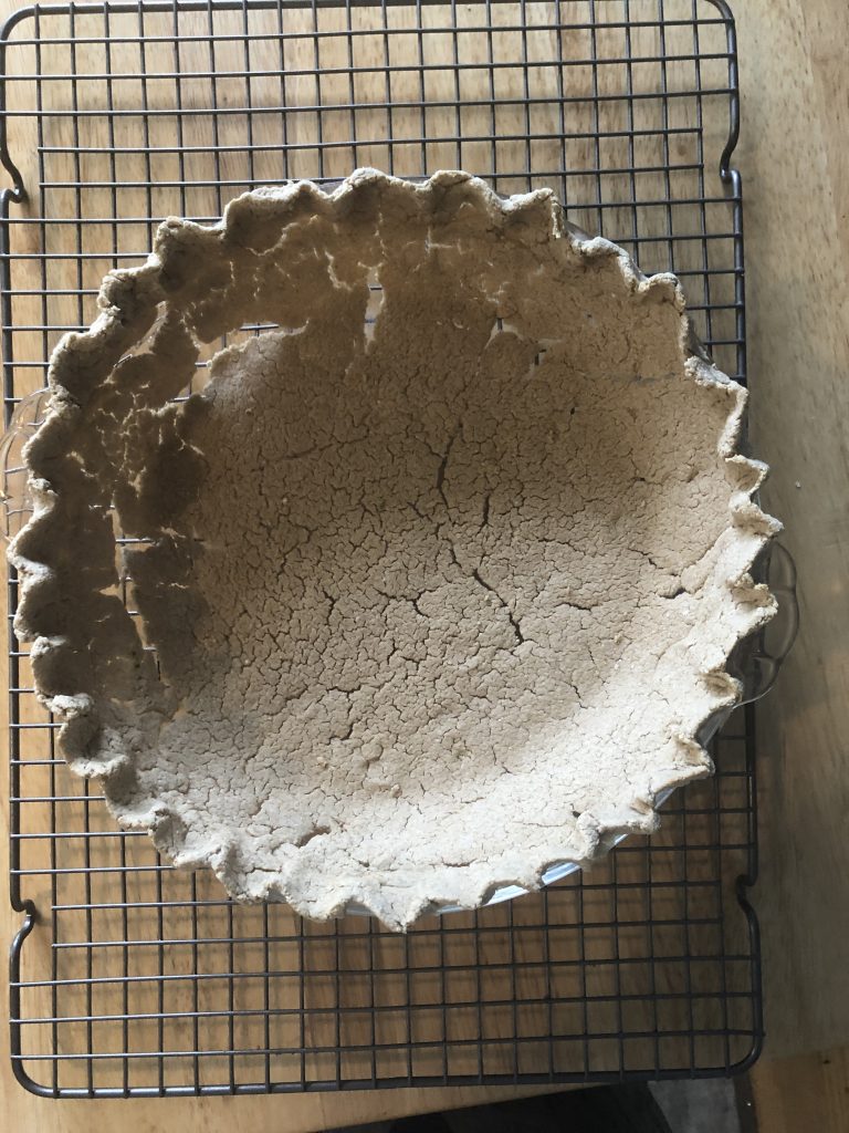 A baked pie crust, the shell is very light and cracked, there are big gaps on the sides.