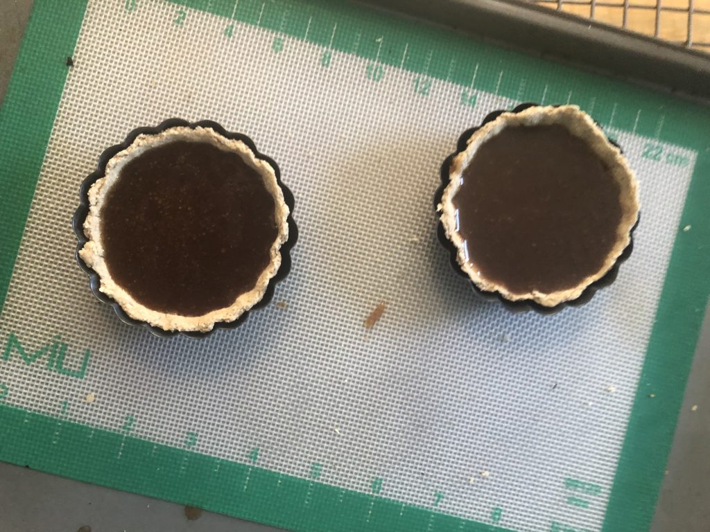 Two small tarts with a dark brown filling.