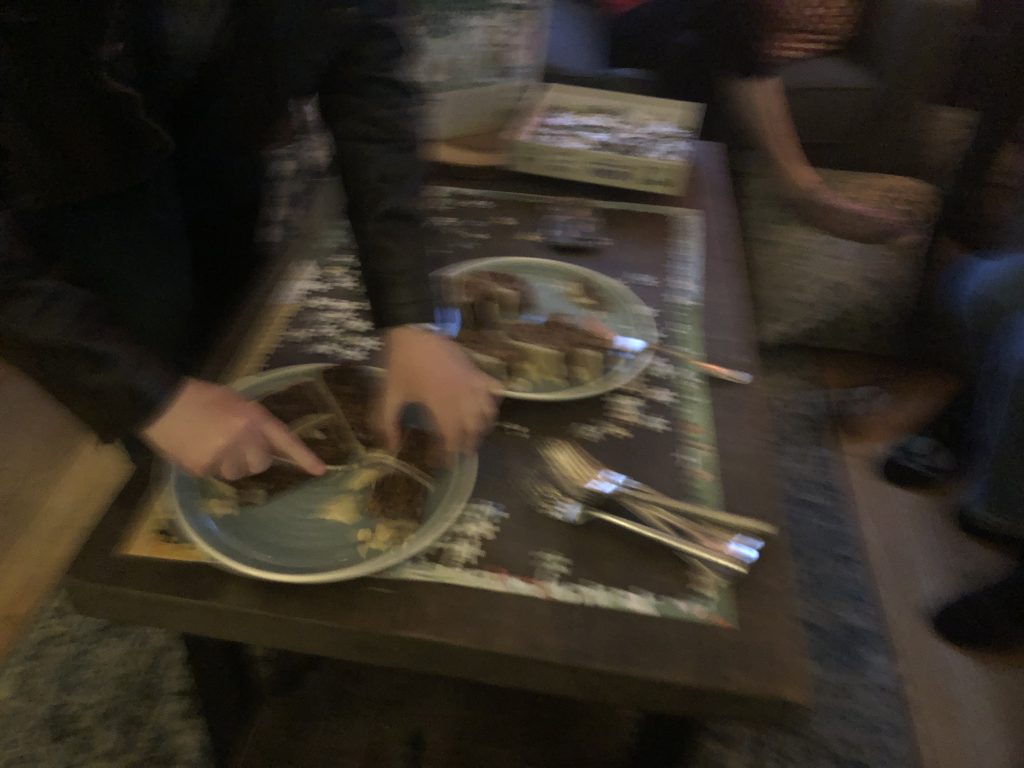 A blurry view of someone passing out slices of fruit cake.
