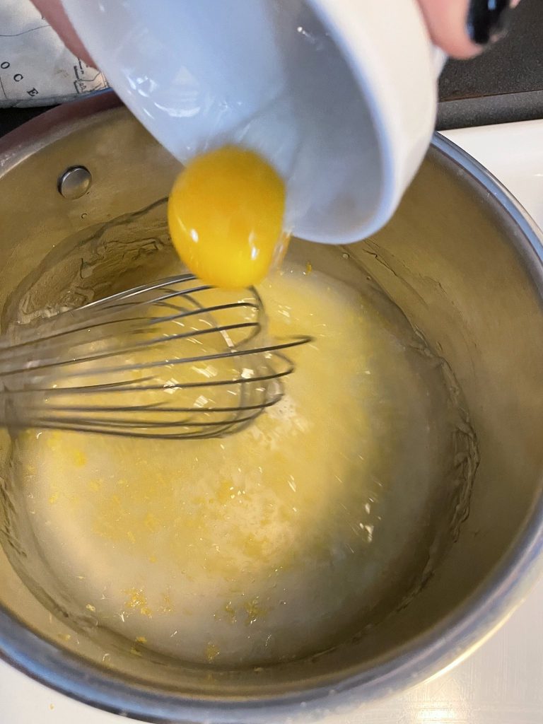 Pouring an egg yolk into a pot full of a water mixture.
