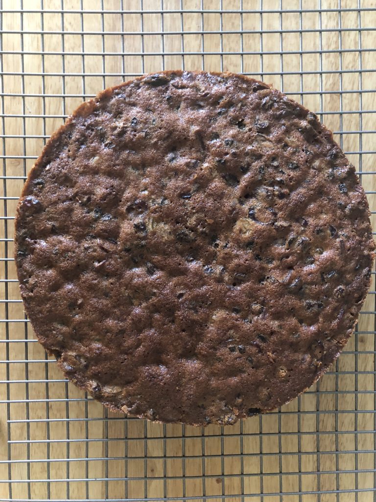 A dark brown, round fruit cake with lots of visible dried fruit.