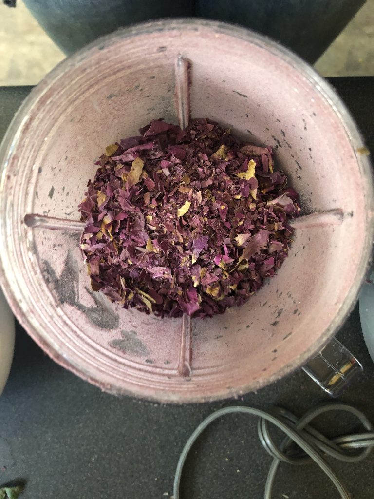 A blender full of crushed dried bale pink rose petals.