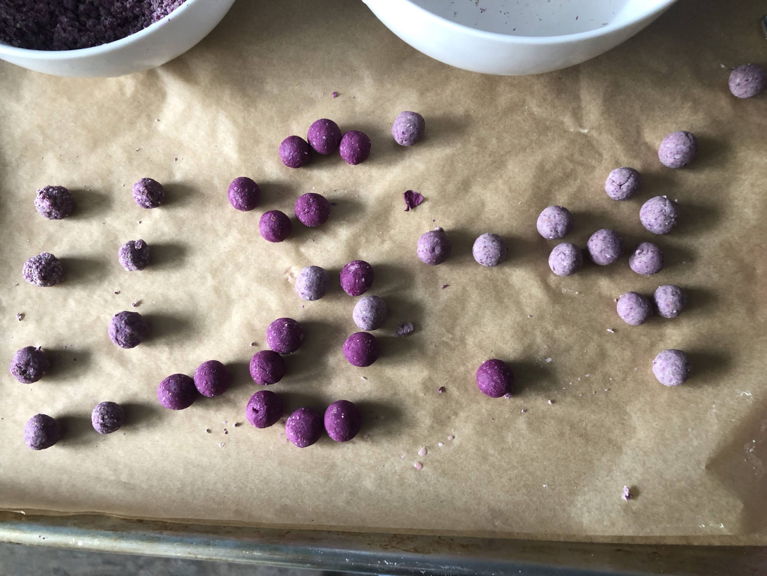 a collection of round balls of purple and purple gray tray on a baking sheet.