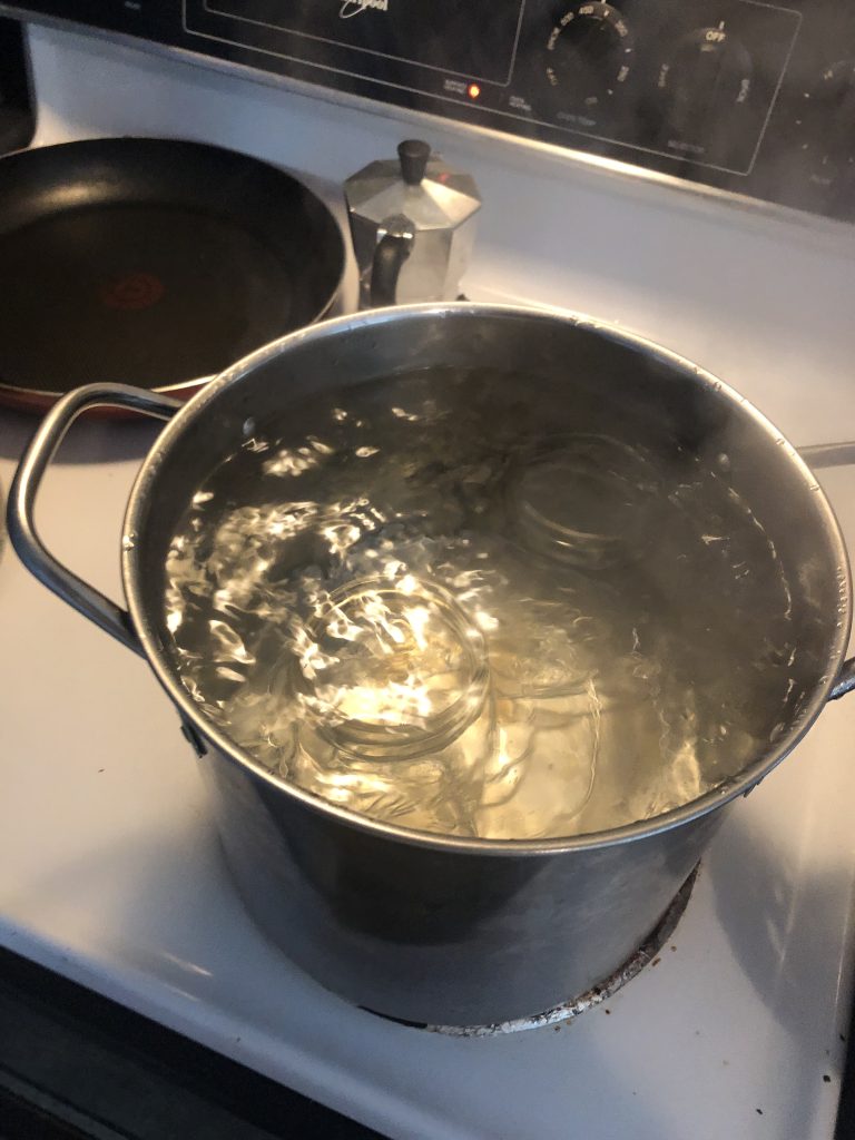 A stock pot full of boiling water and two empty glass jars.